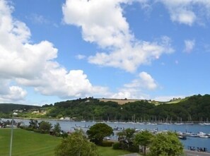 A marina with boats docked, surrounded by greenery and hills.