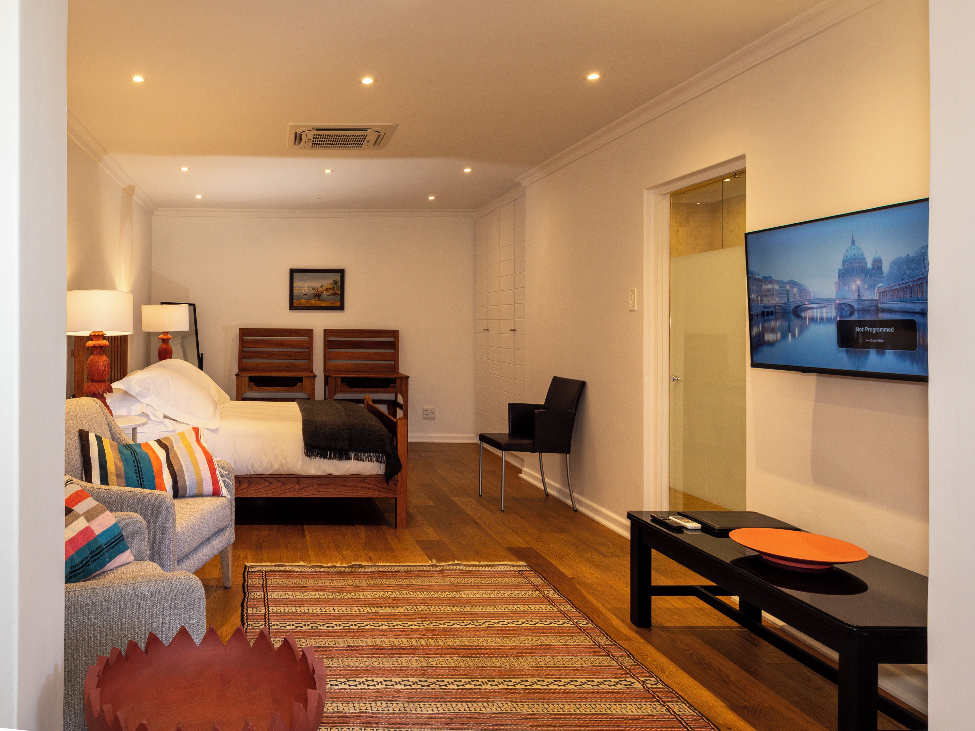 Ein Hotelzimmer mit einem Bett, zwei Stühlen, einem Sofa, einem Fernseher und einem kleinen Tisch.