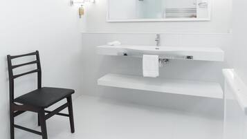 Un bagno moderno con una sedia in legno scuro, un lavandino bianco e uno specchio sopra.