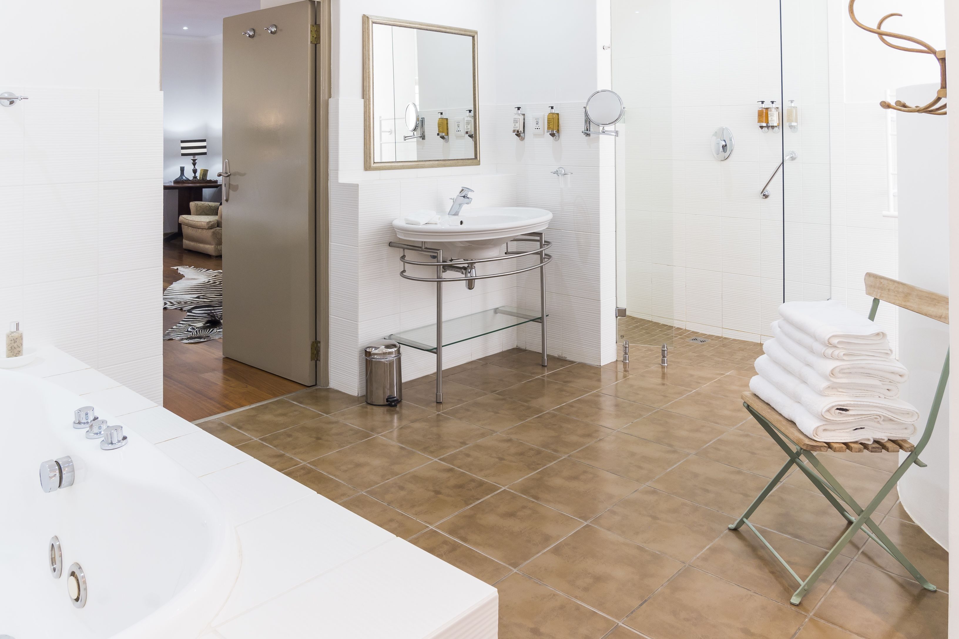 A modern bathroom with a large bathtub, a sink with a mirror, and a shower area.