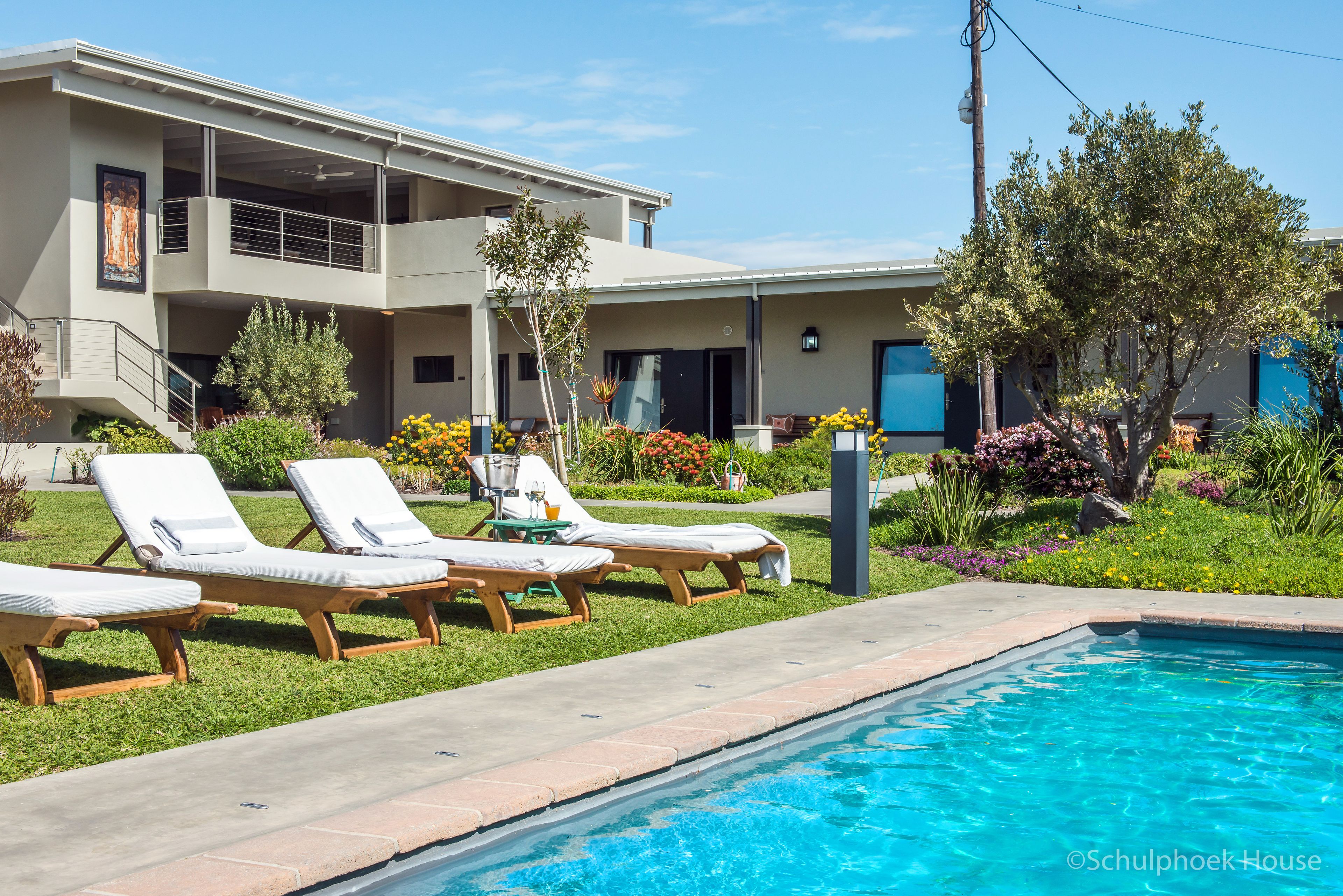 Een buitenzwembad, parasols bij het zwembad en ligstoelen