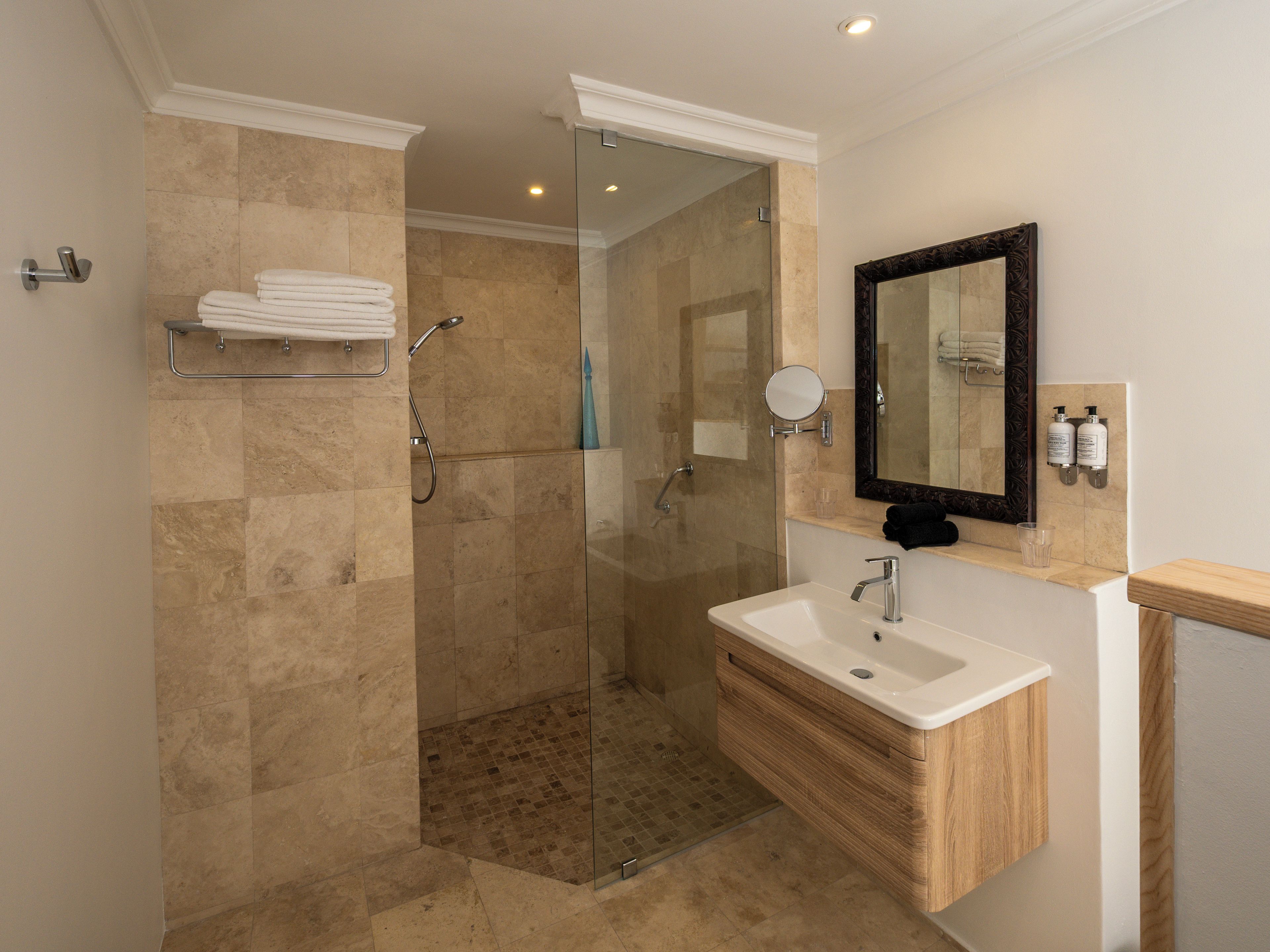 A modern bathroom with a glass-enclosed shower, a wooden vanity, and a large mirror.