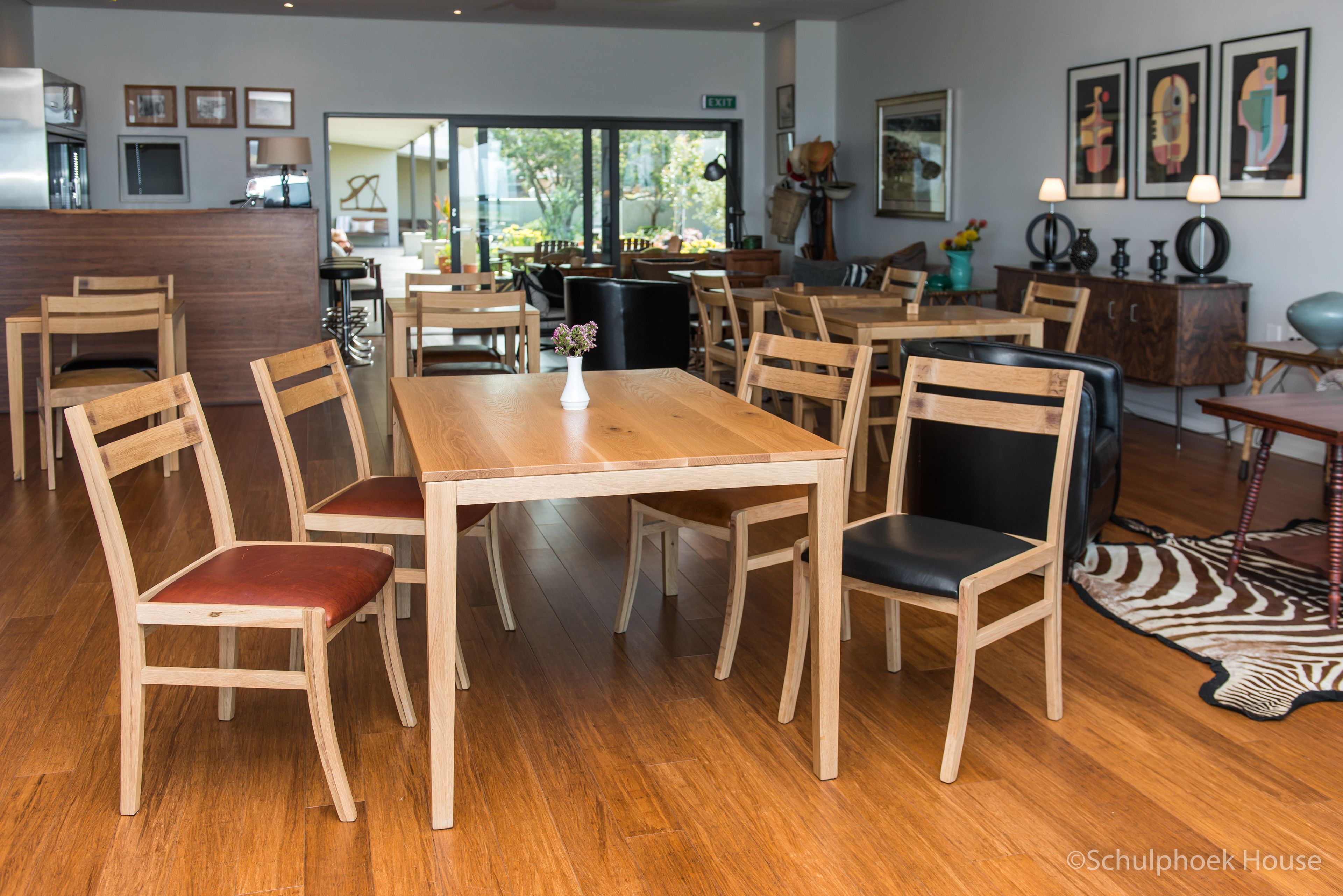 Uma sala de jantar espaçosa com mesas e cadeiras de madeira, uma poltrona de couro preto e um tapete de zebra.