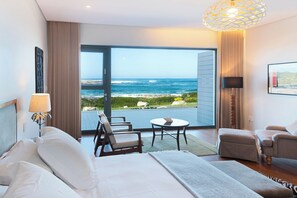 A hotel room with a large balcony, a bed, two armchairs, a small table, and a lamp. - Schulphoek House (Hermanus)