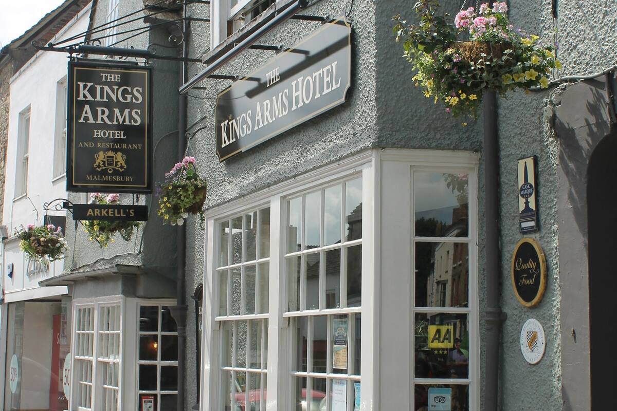 The Kings Arms Hotel with a traditional facade, large windows, and hanging flower baskets.