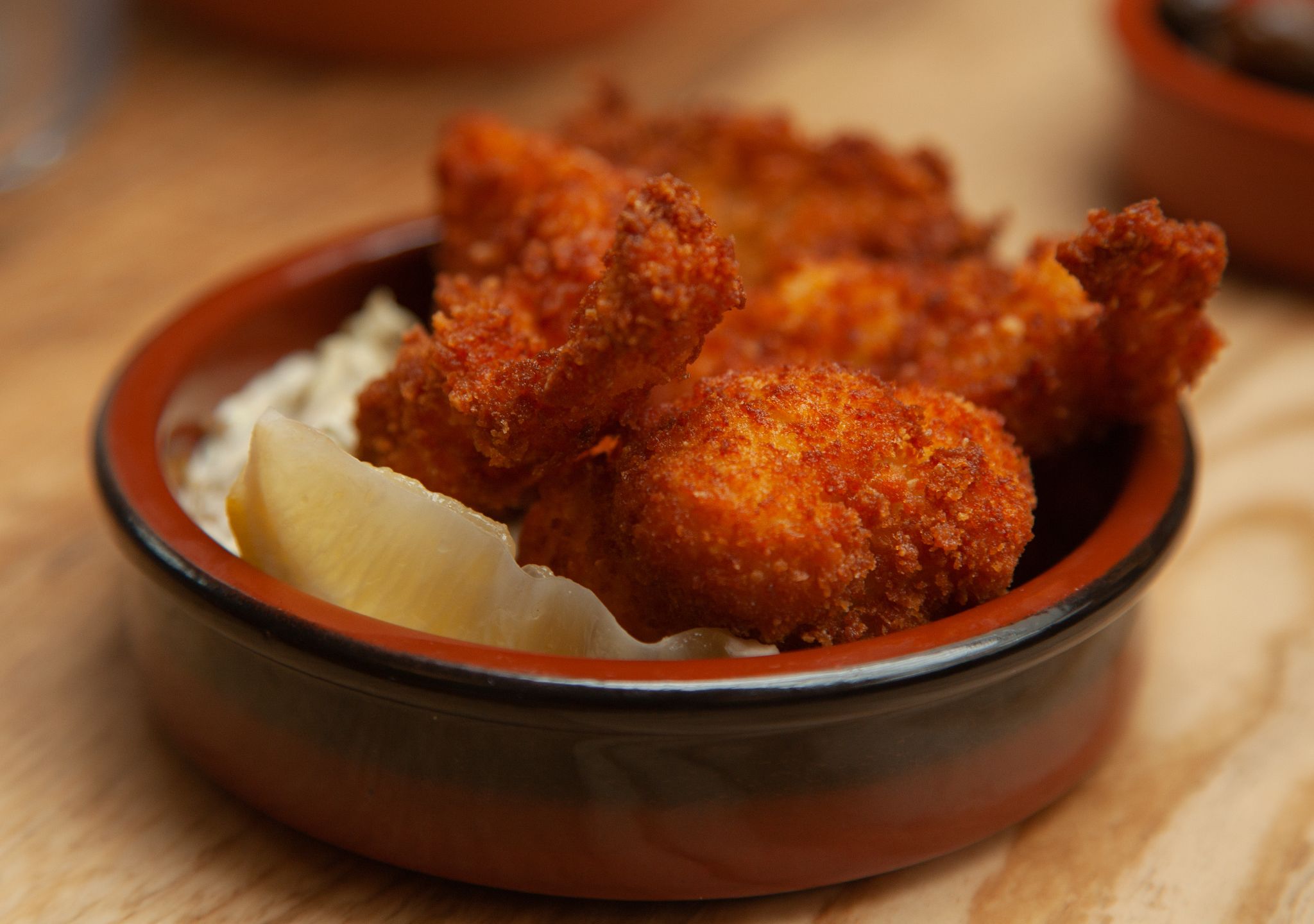 Un bol de poulet frit accompagné d’une tranche de citron.