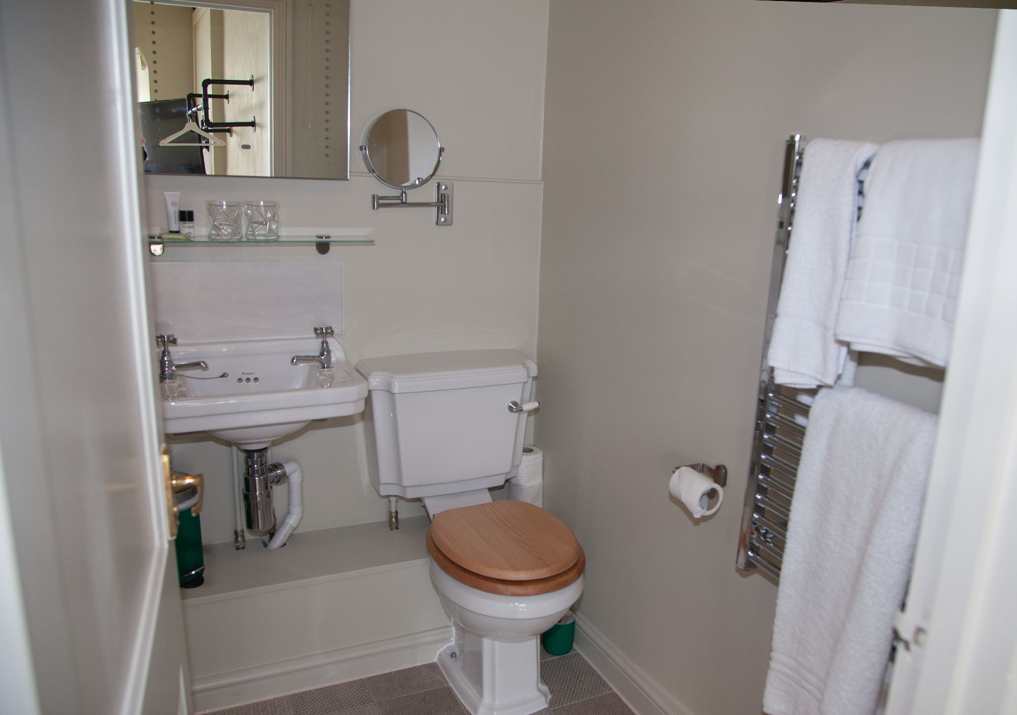 A compact bathroom with a toilet, sink, and mirror.