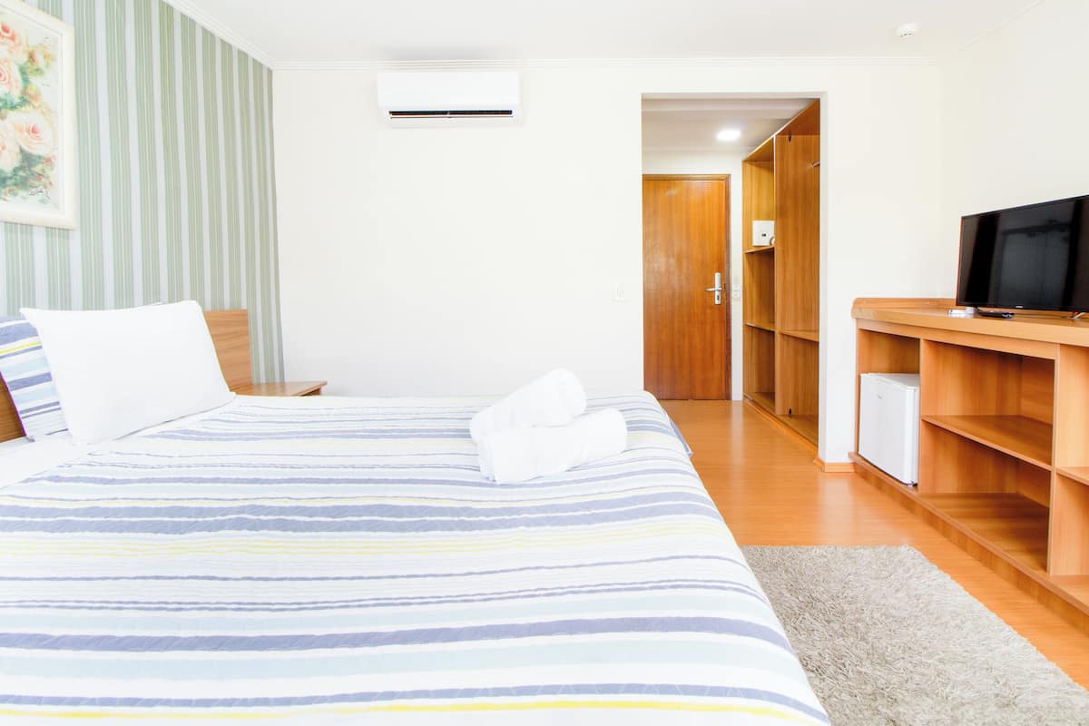 Une chambre d’hôtel comprenant un lit, une télévision, une armoire et une porte donnant sur une autre pièce.