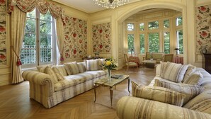Un salón amplio con un sofá grande, sillones, una mesa de centro y una araña.