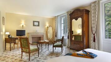 A hotel room with a bed, a television, a fireplace, and a large mirror.