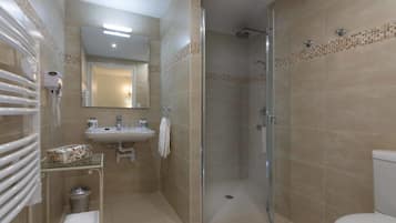 A bathroom with a glass-enclosed shower, a sink, and a toilet.