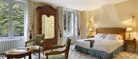 A hotel room with a large bed, two bedside tables with lamps, a chair, a mirror, and a window with curtains.
