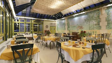 A dining area with tables set for breakfast, featuring yellow tablecloths and black chairs.
