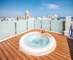 Uma banheira de hidromassagem em um deck de madeira, com vista para o horizonte da cidade.