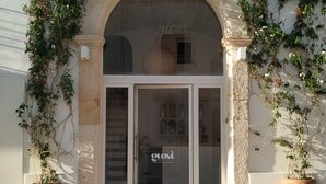 A building entrance with a glass door, flanked by two large terracotta pots.