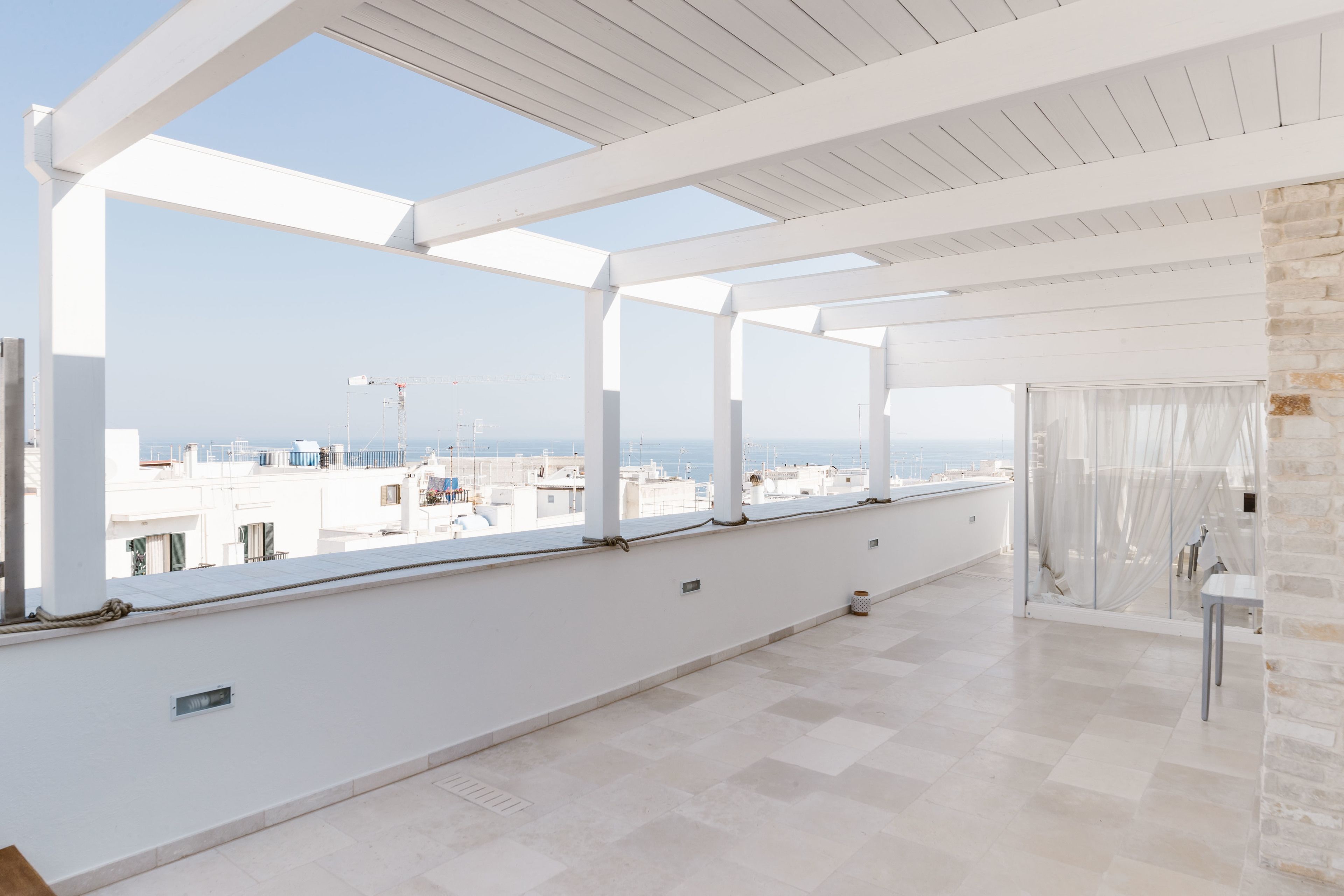 Un balcón amplio con vistas despejadas del horizonte urbano, barandillas blancas y un muro de piedra.