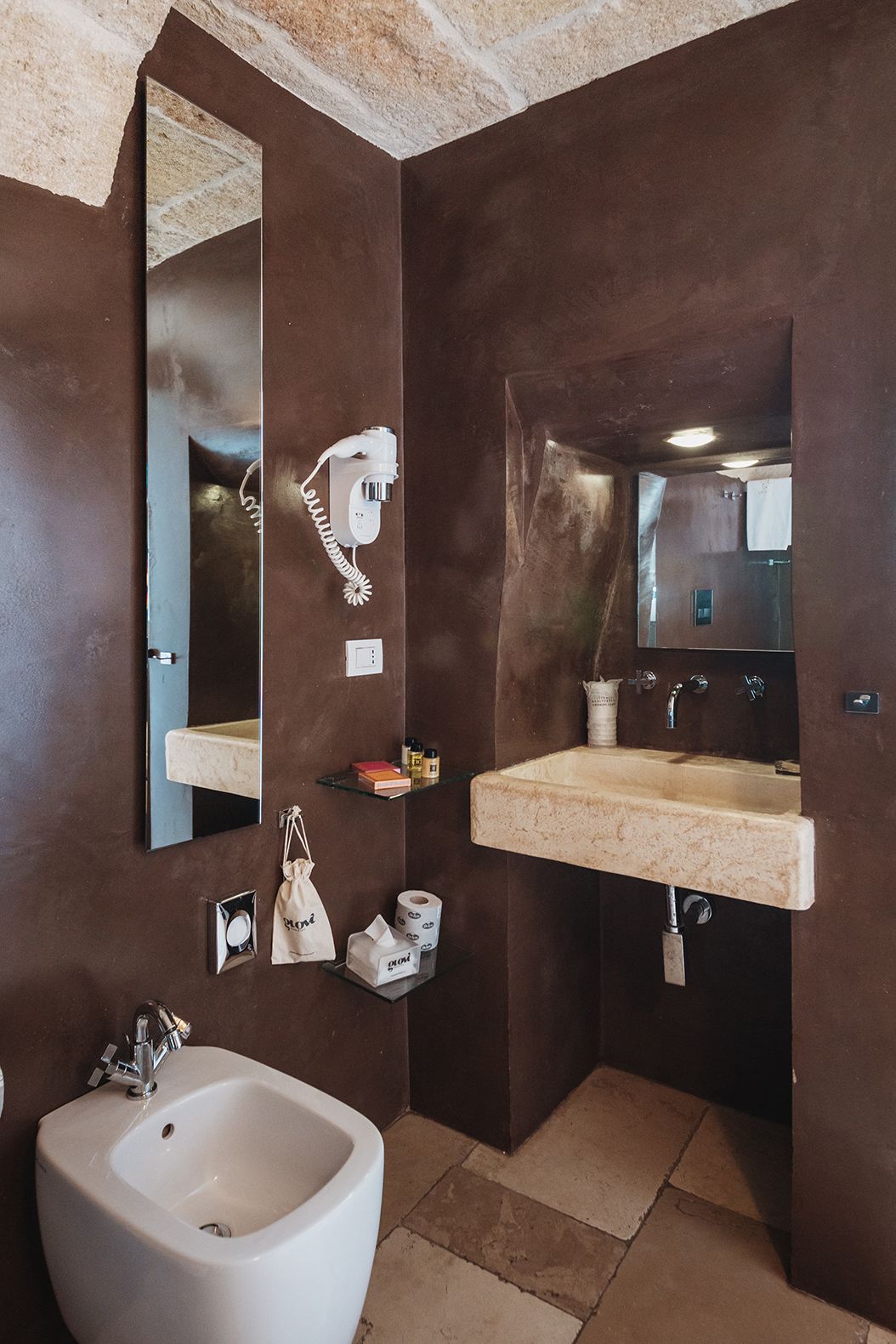 Un baño con un espejo grande, un bidé, un lavamanos y un perchero para toallas.