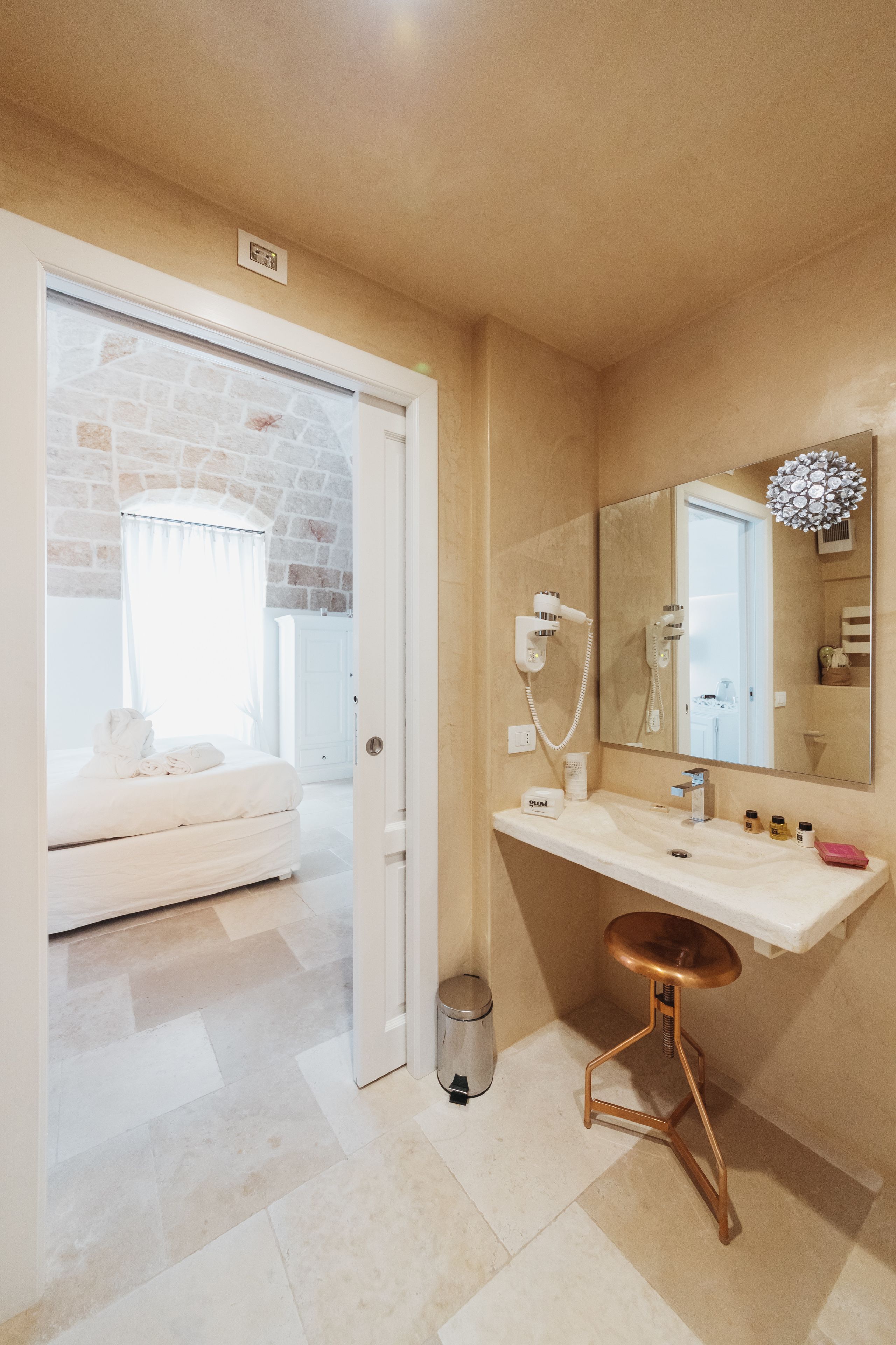 Een badkamer met een wit wastafel, een spiegel, een haardroger en een handdoek op de vloer.