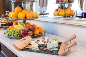 Un bufé con diversas frutas, quesos y postres.