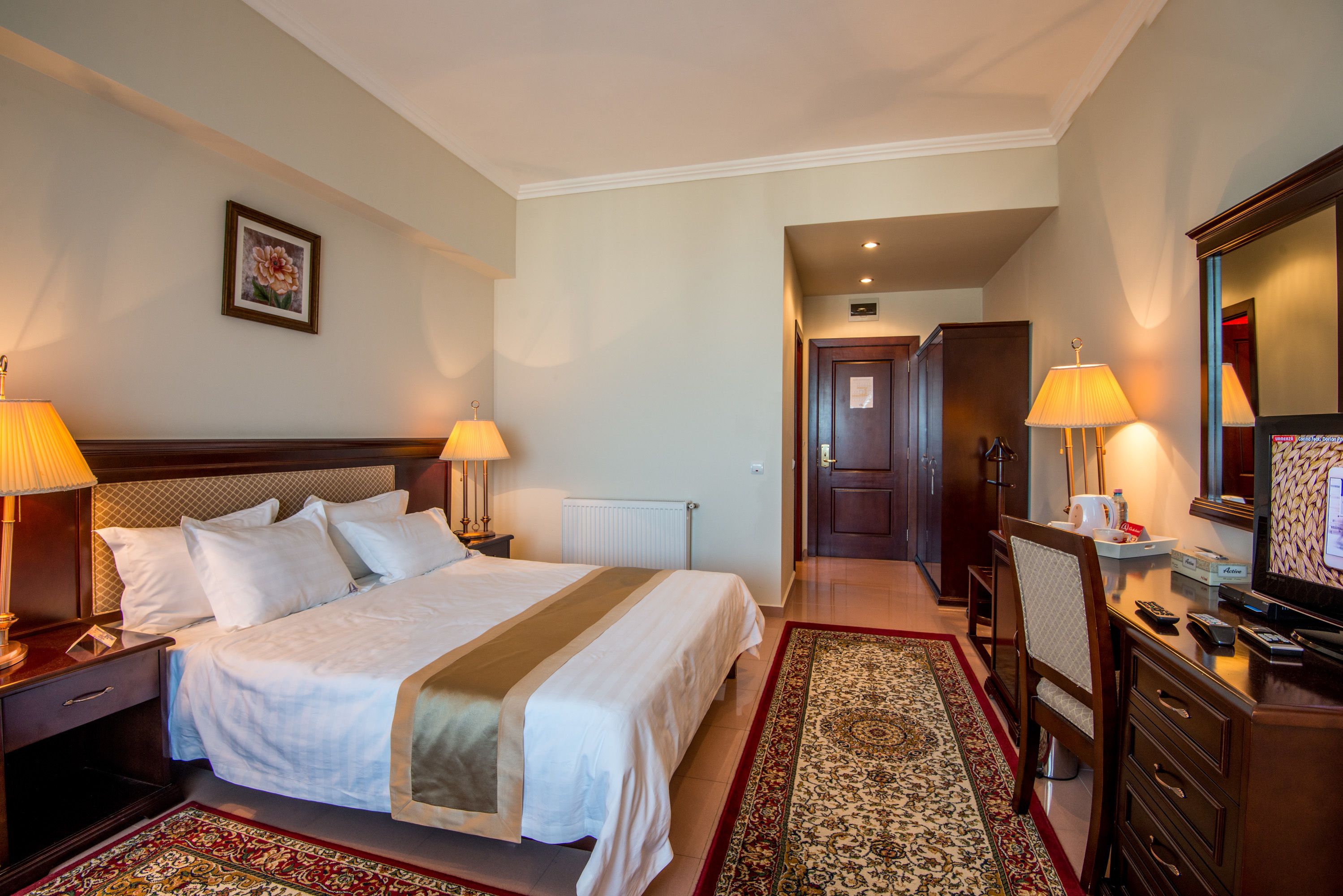 Une chambre d’hôtel avec un grand lit, des lampes de chevet, un bureau avec une chaise, une télévision et un miroir.