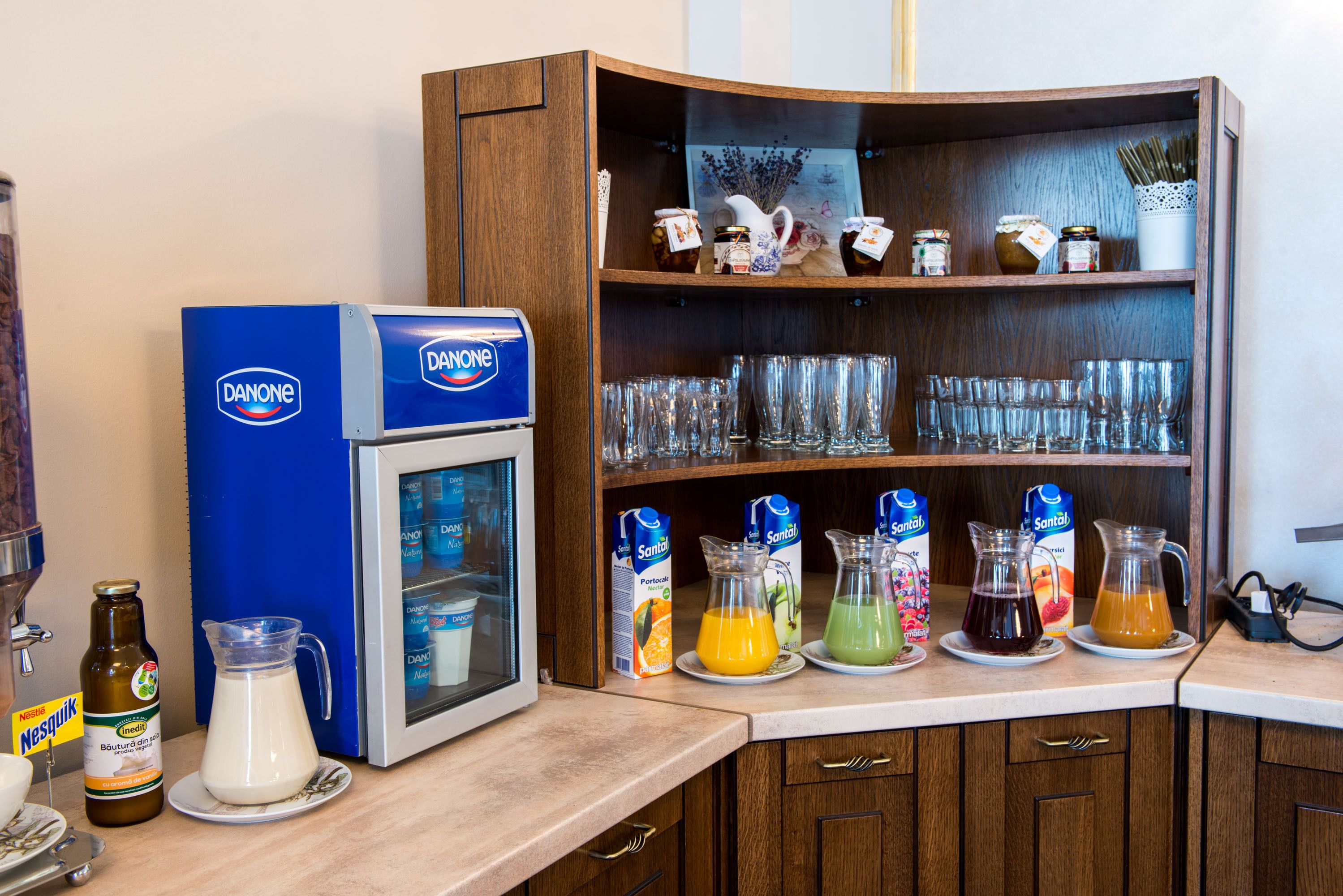 A kitchen counter with a coffee machine, milk jug, and various juice pitchers.