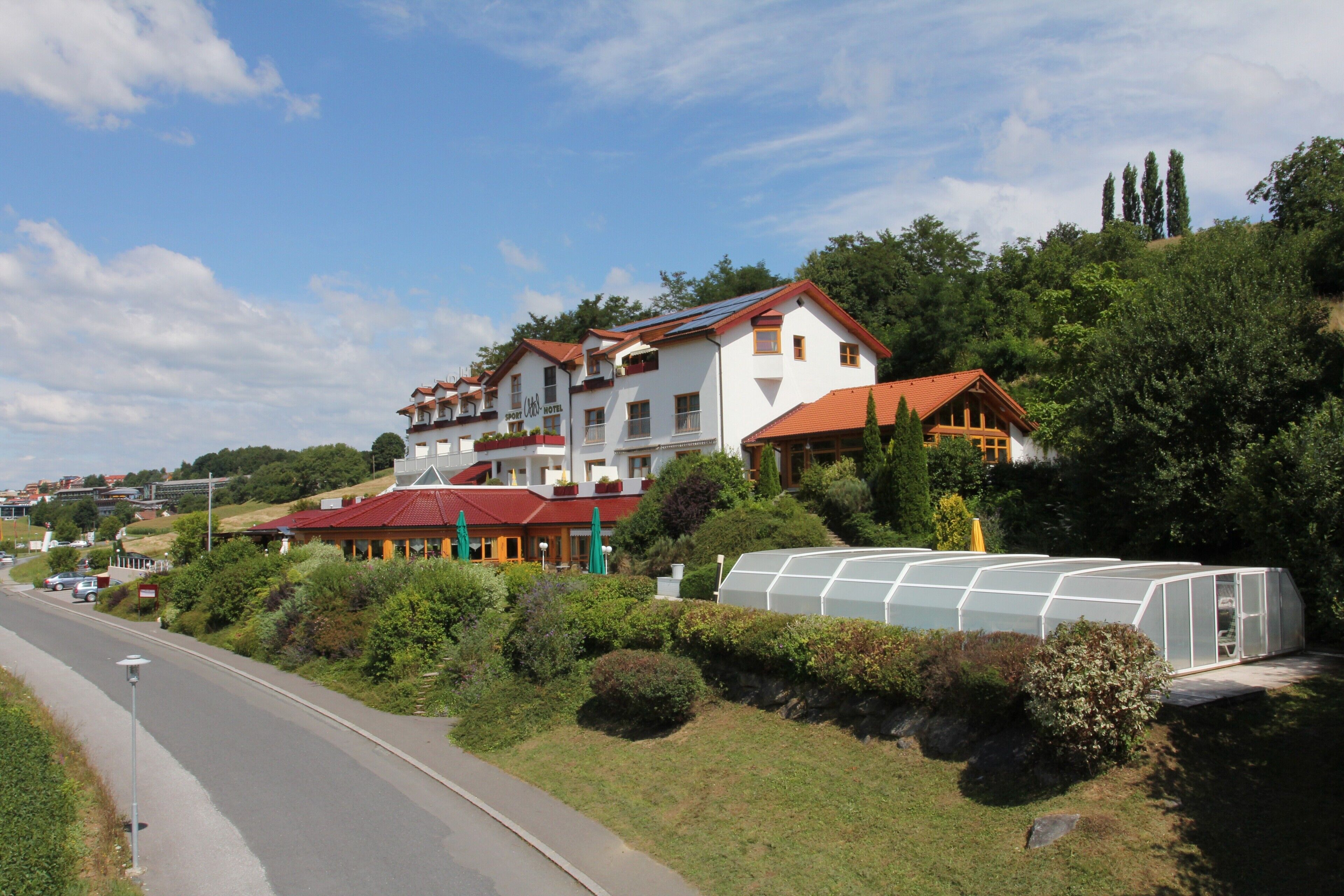 Um hotel grande com vários edifícios, uma estrada em primeiro plano e vegetação ao redor.