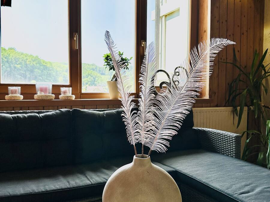 Ein Zimmer mit großem Fenster, einer Couch und einem runden Tisch mit dekorativer Vase.