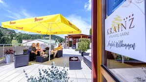 An outdoor seating area with yellow umbrellas, wicker furniture, and potted plants. - Vital Hotel Krainz mit Nebenhaus Familien Hotel (Jennersdorf)