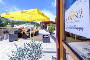 An outdoor seating area with yellow umbrellas, wicker furniture, and potted plants. - Vital Hotel Krainz mit Nebenhaus Familien Hotel (Jennersdorf)