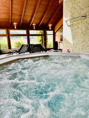 A hot tub with a wooden ceiling and large windows.