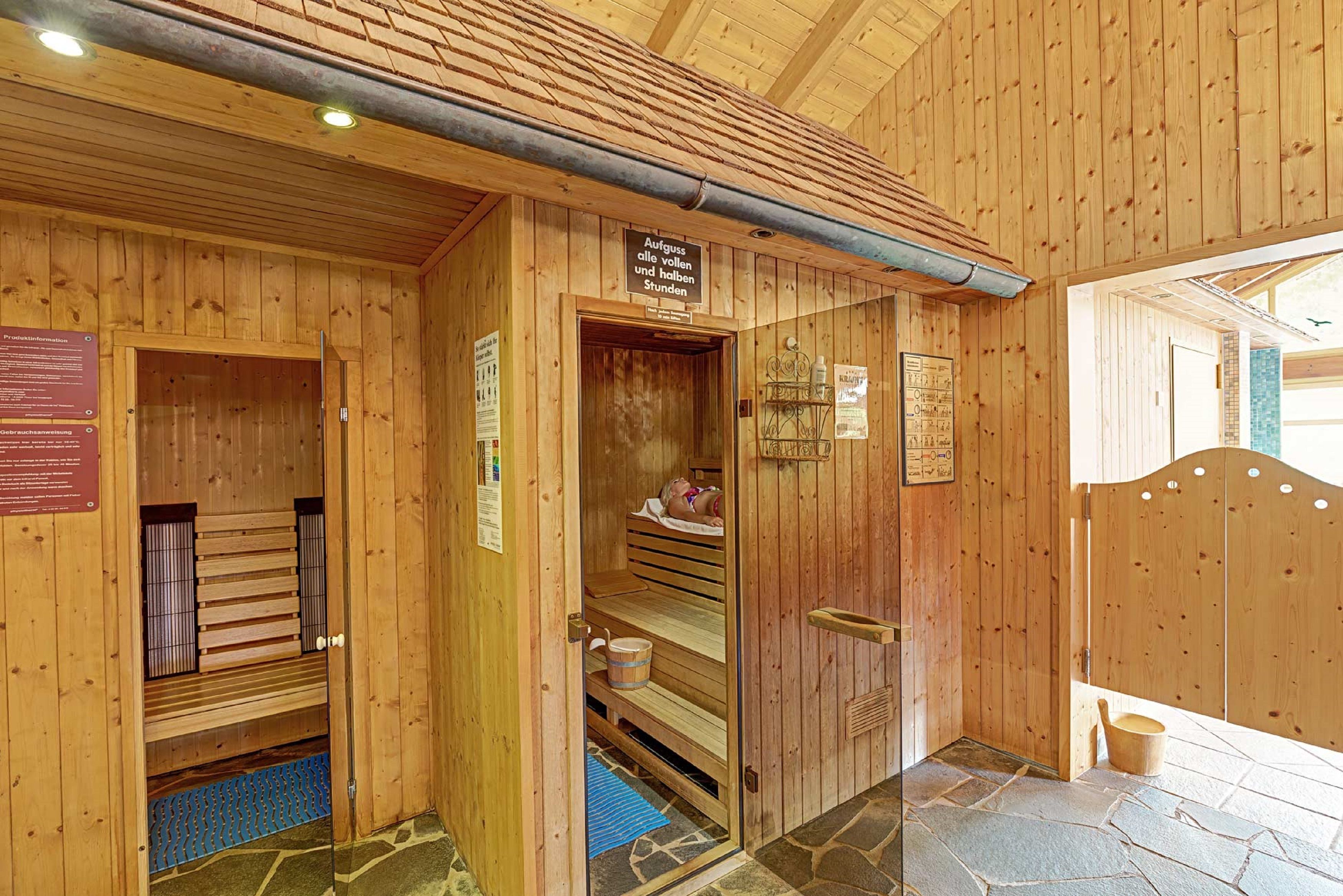 Un sauna en bois avec des bancs, une porte en bois et un sol en pierre.