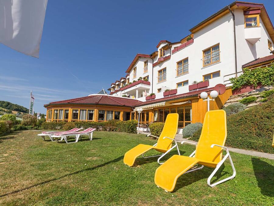 Un hotel con un amplio espacio exterior que incluye sillones amarillos y una zona de estar techada.
