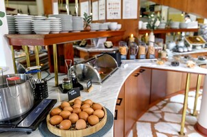 A buffet setup with a variety of dishes, a large pot, and a bowl of eggs.