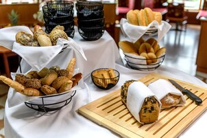 Una mesa con panes y pasteles varios, un cuchillo y tazones negros.
