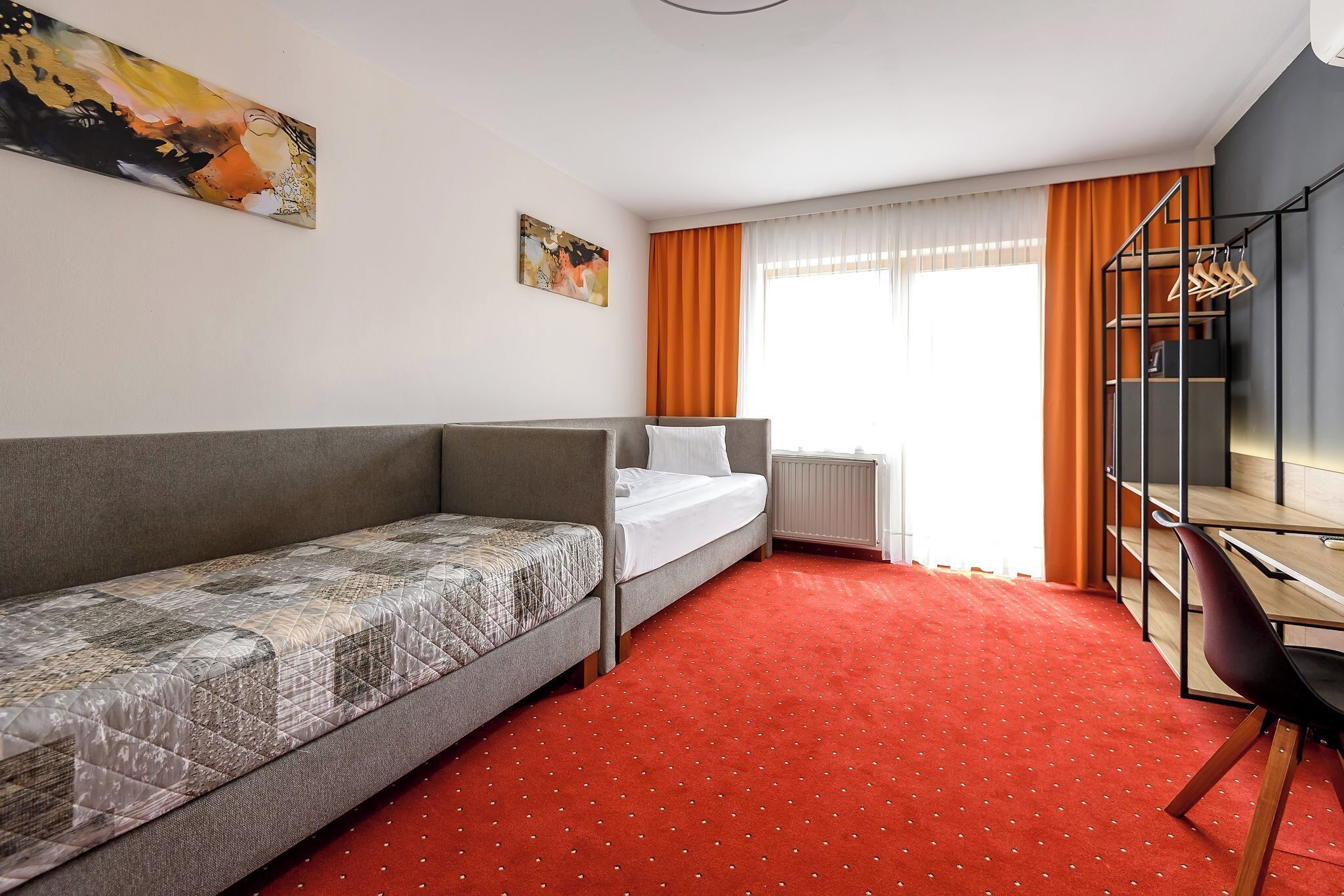 Una habitación de hotel con una cama individual, un sofá, un escritorio y una silla.