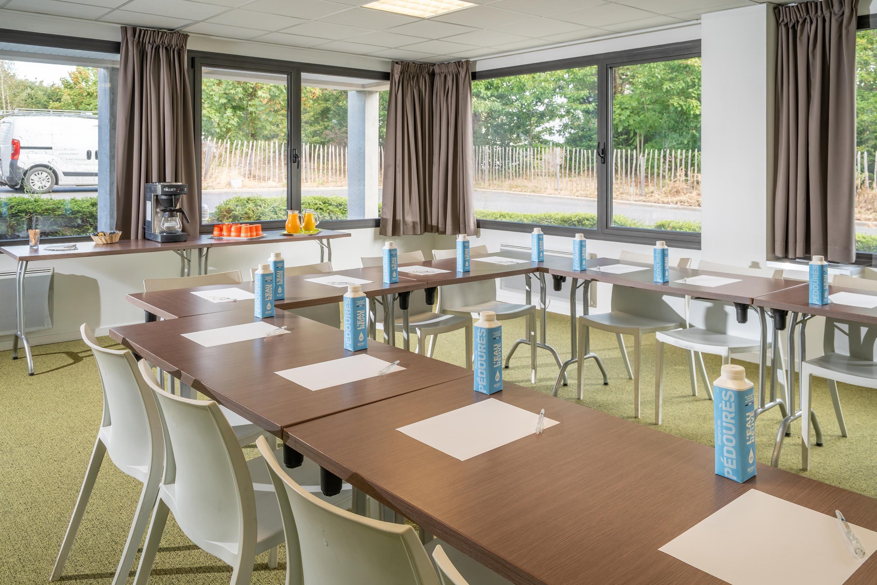 A conference room with tables, chairs, and water bottles.