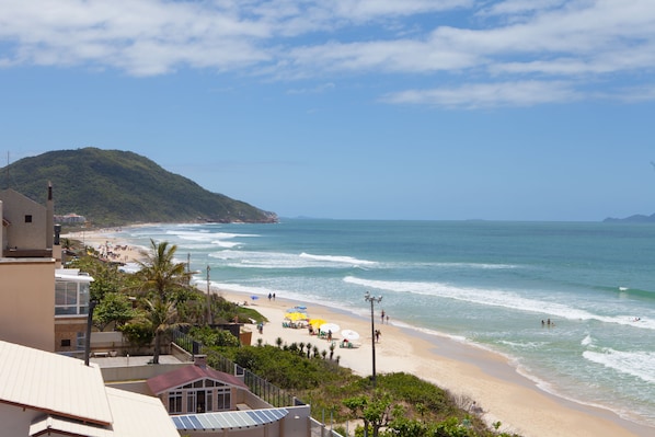 A beach with a view of the ocean and a hill in the background. - Palm Beach Apart Hotel (Florianópolis)