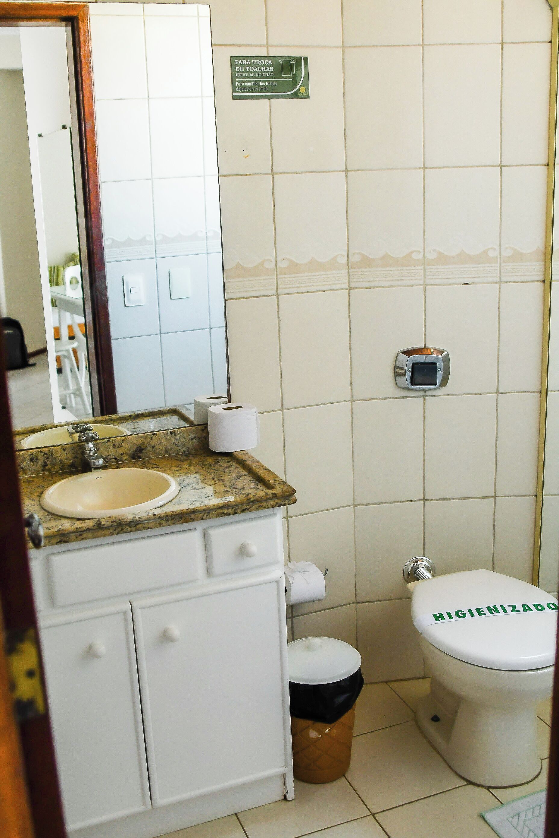 A bathroom with a sink, toilet, and a trash bin.