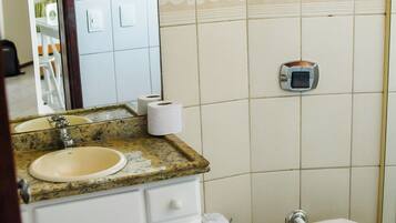 A bathroom with a sink, toilet, and a trash bin.