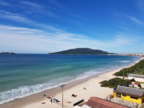 Una playa con un bote, un pequeño edificio y una isla distante.