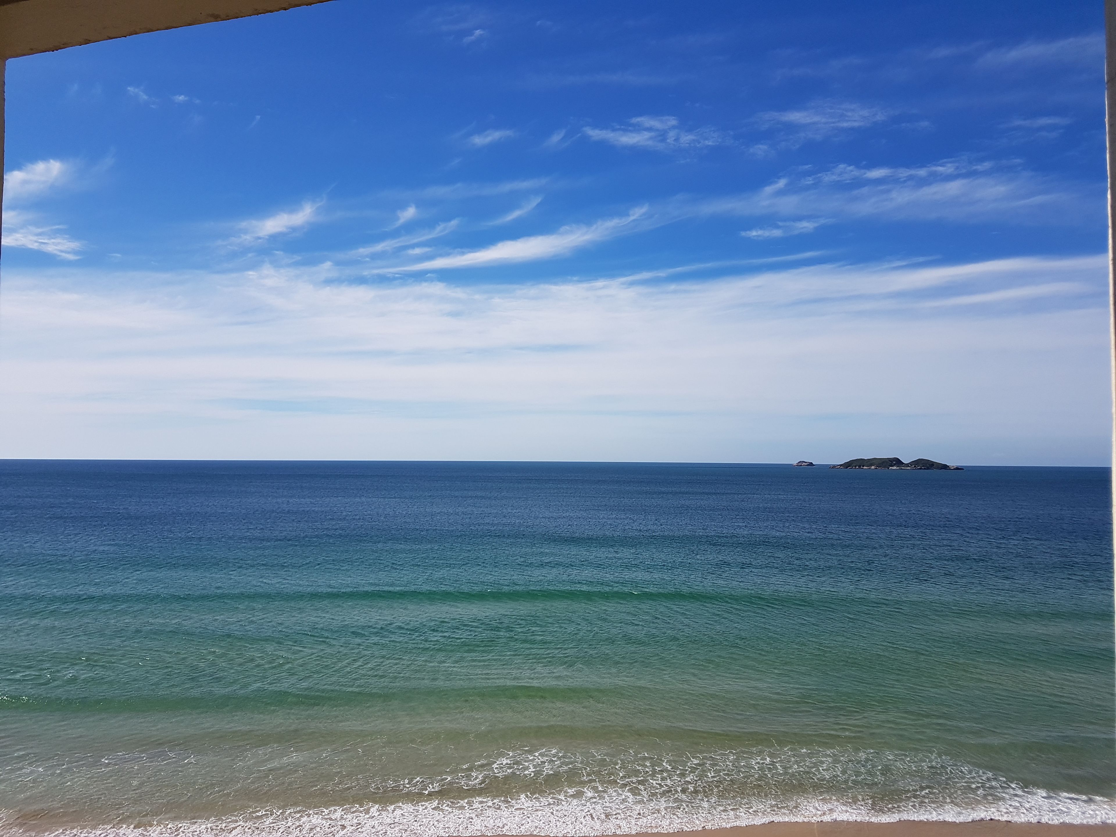 Vista del océano con una isla distante y cielos despejados.