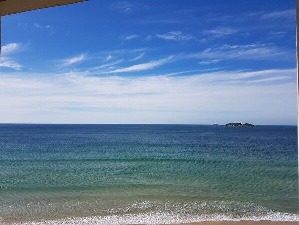 Vista del océano con una isla distante y cielos despejados.