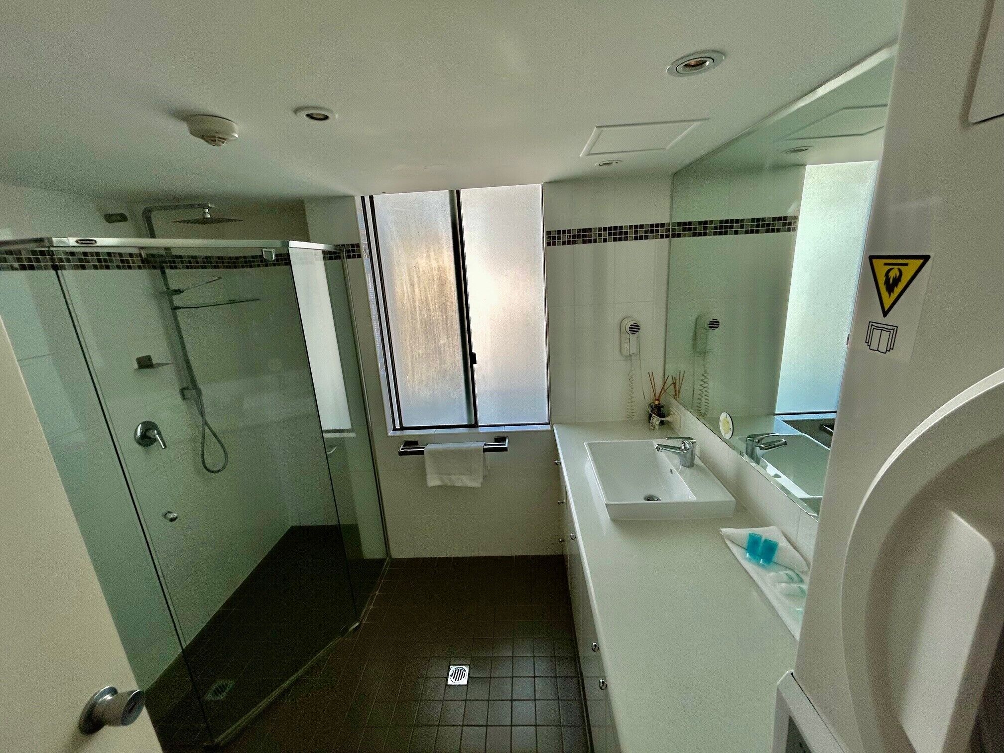 A bathroom with a glass-enclosed shower, a sink, and a mirror.
