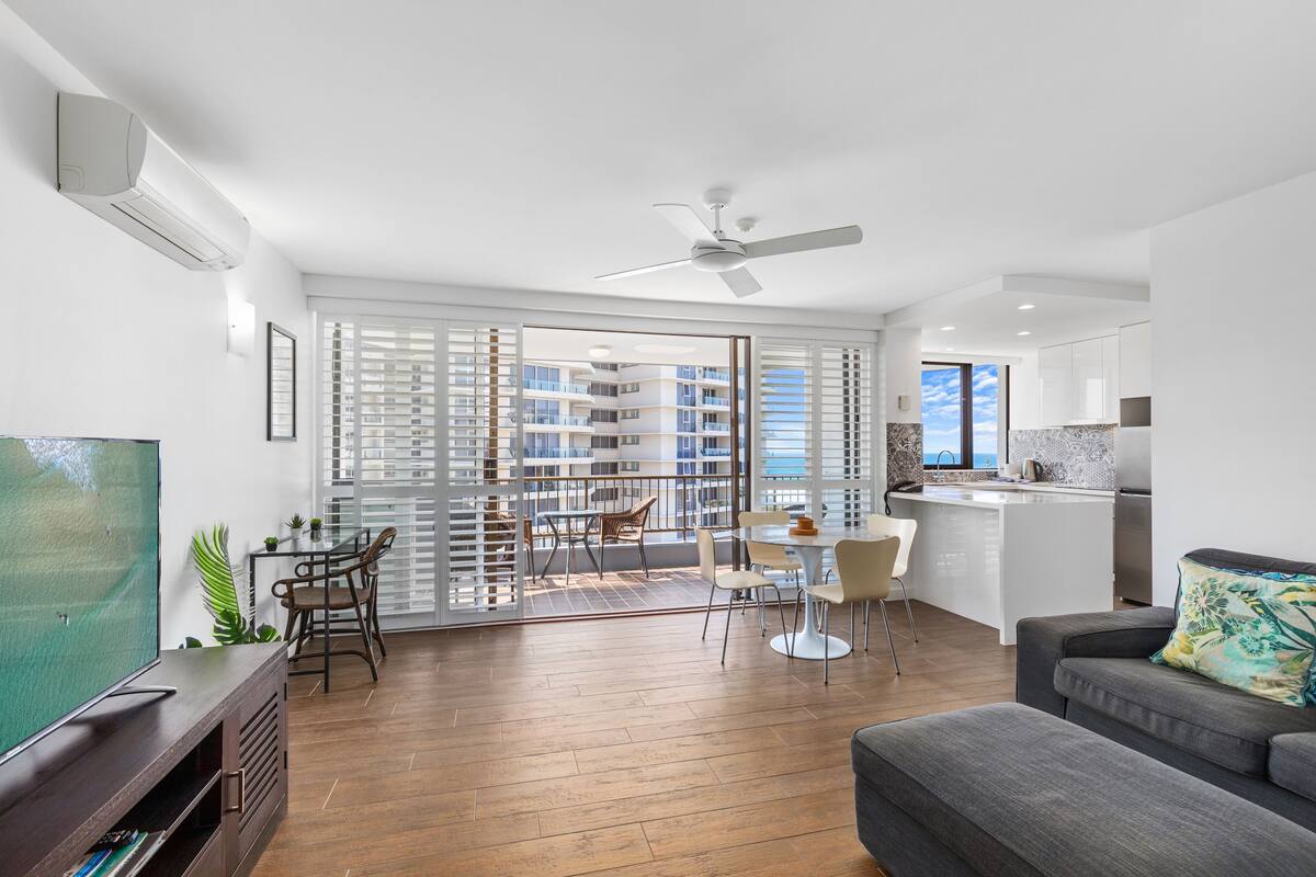 A modern apartment with a balcony, a dining area, a living room, and a kitchen.