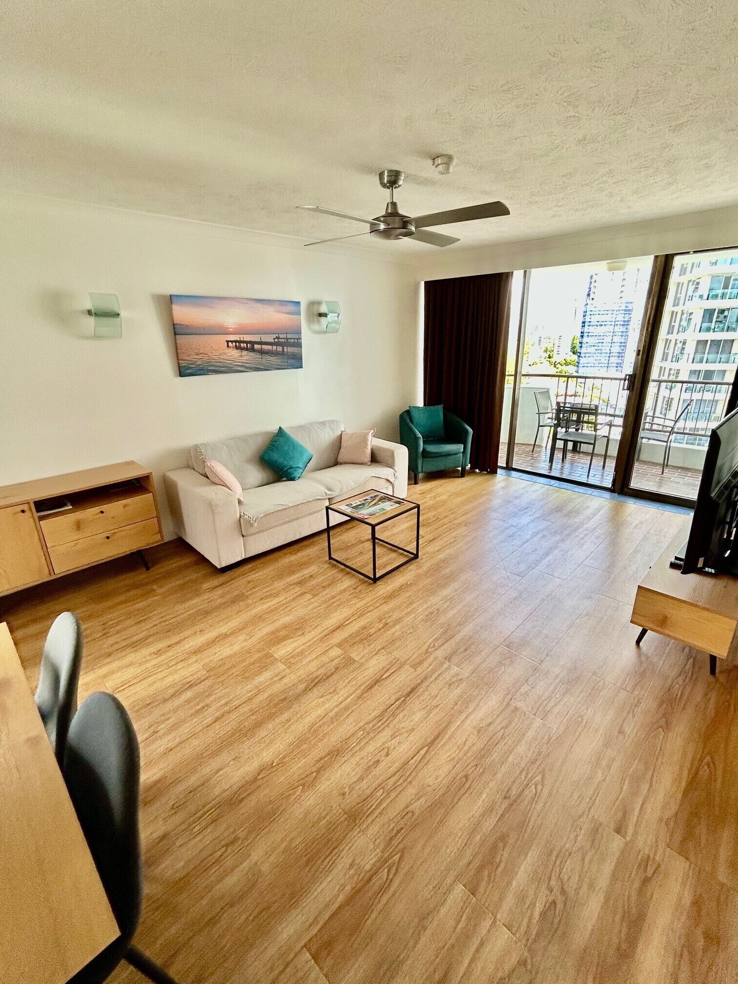 Een moderne woonkamer met een bank, fauteuil, salontafel en plafondventilator.
