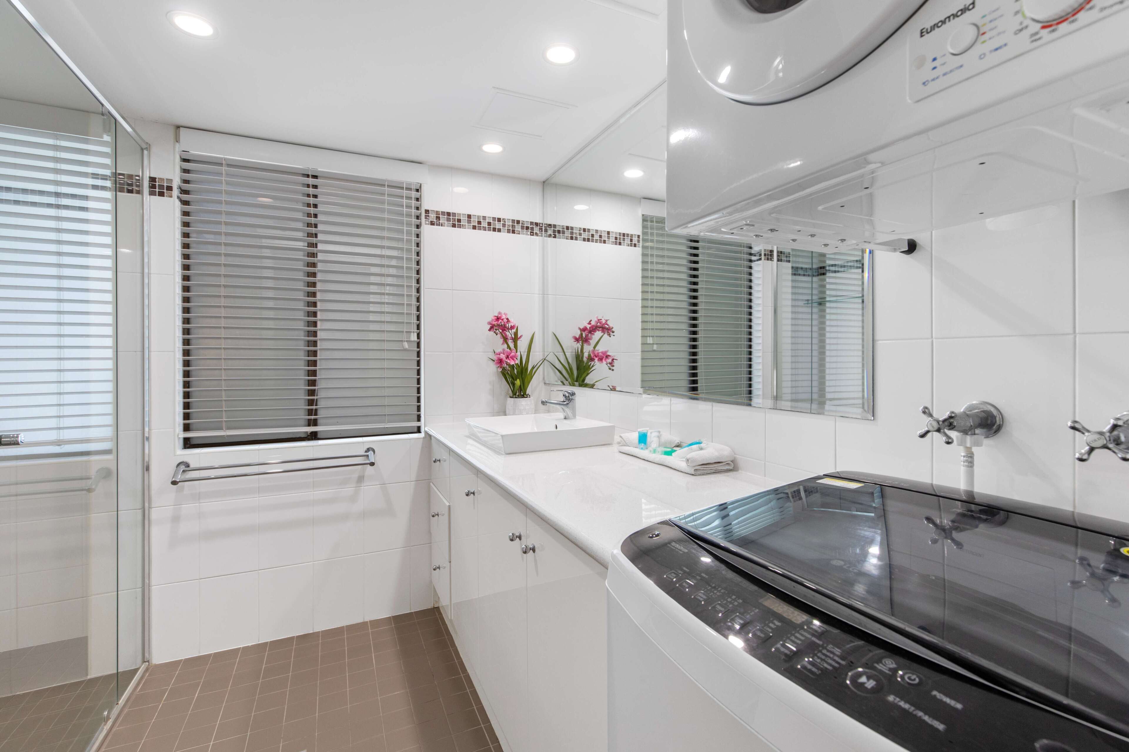 Une salle de bain moderne avec une douche à parois de verre, un lavabo intégré et une baignoire noire.