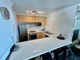 Una cocina moderna con encimera blanca, electrodomésticos de acero inoxidable y armarios de madera.