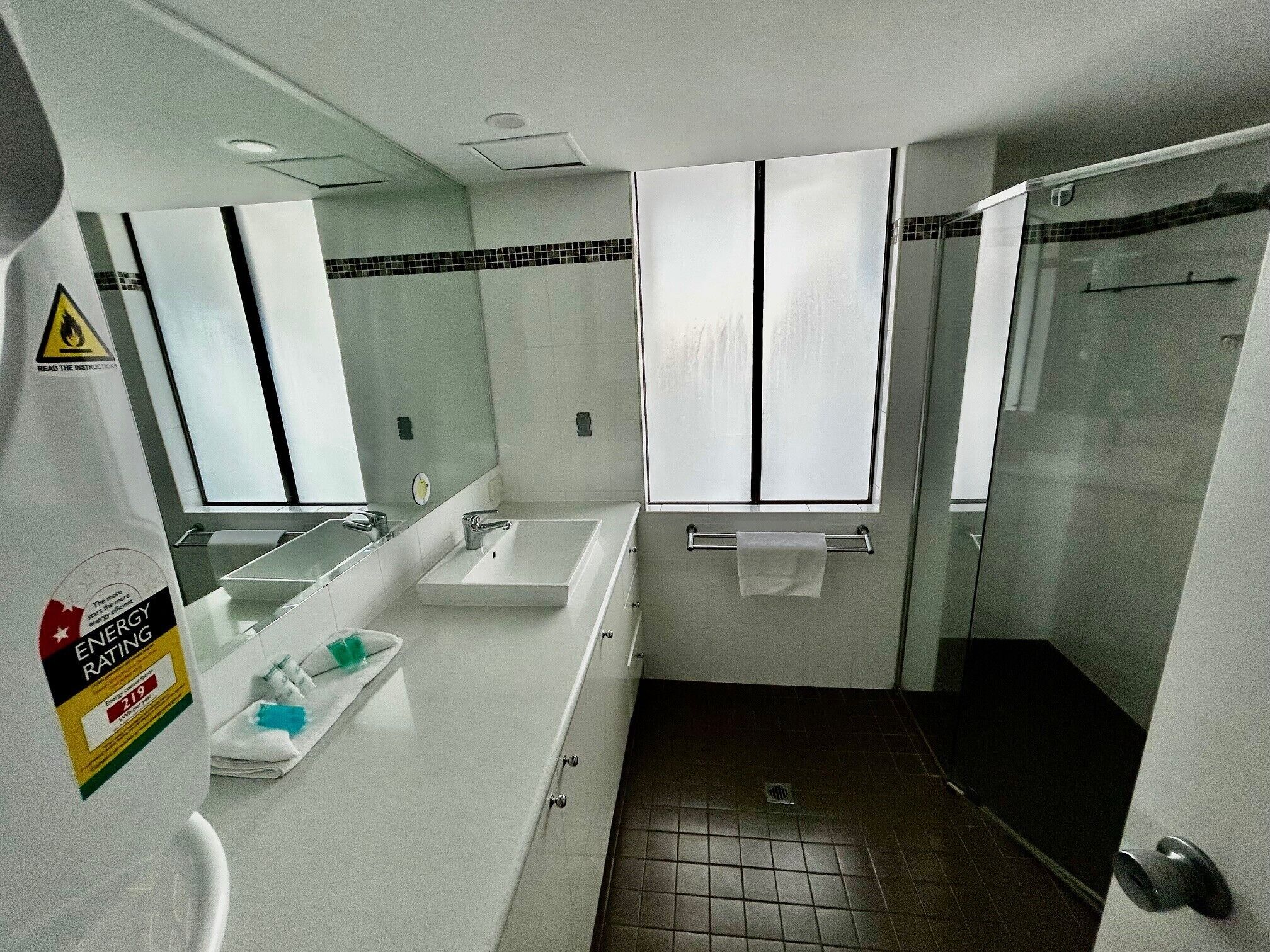 Un baño con lavamanos, espejo, toallero y zona de ducha.