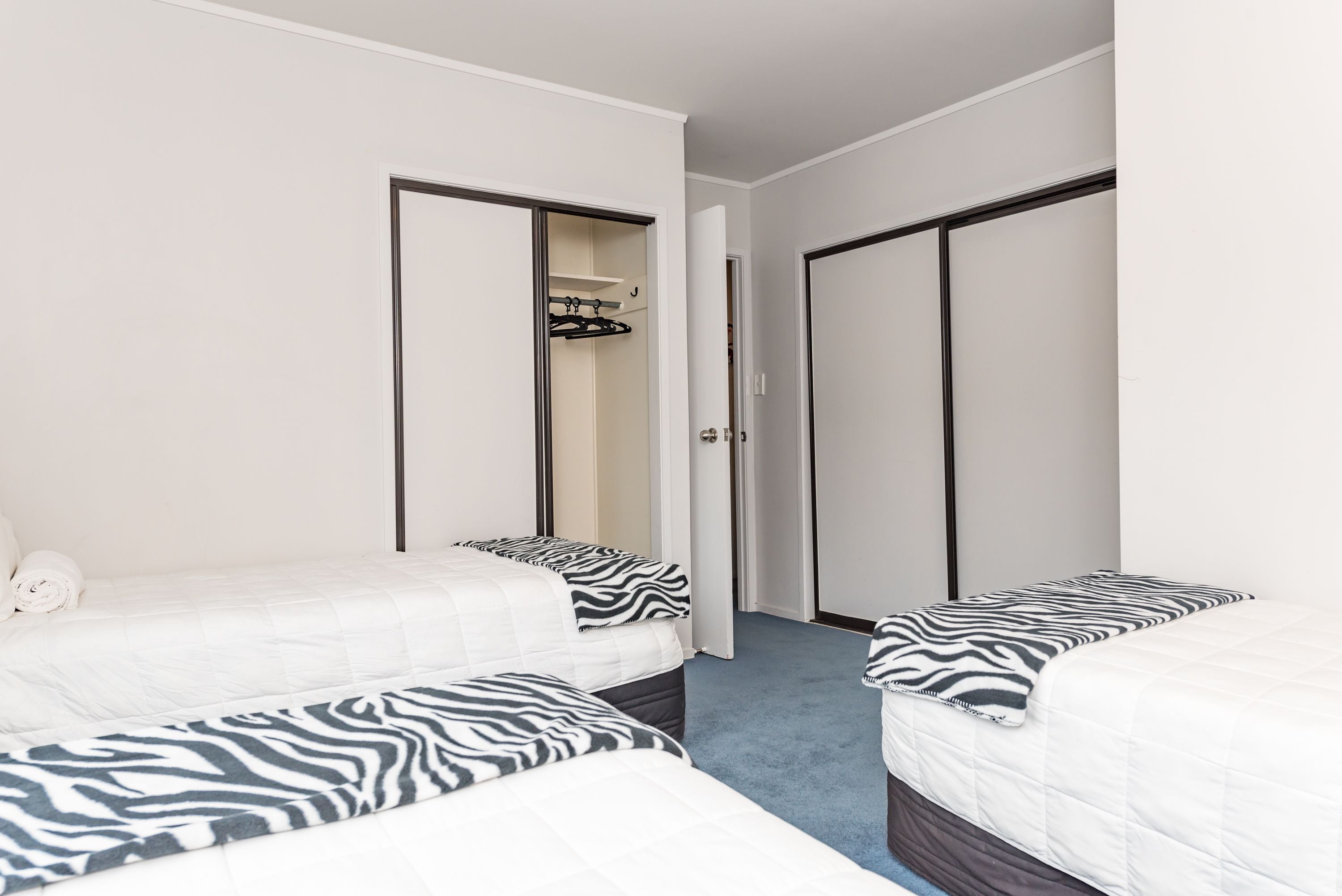 A hotel room with two beds, a wardrobe, and a bathroom.
