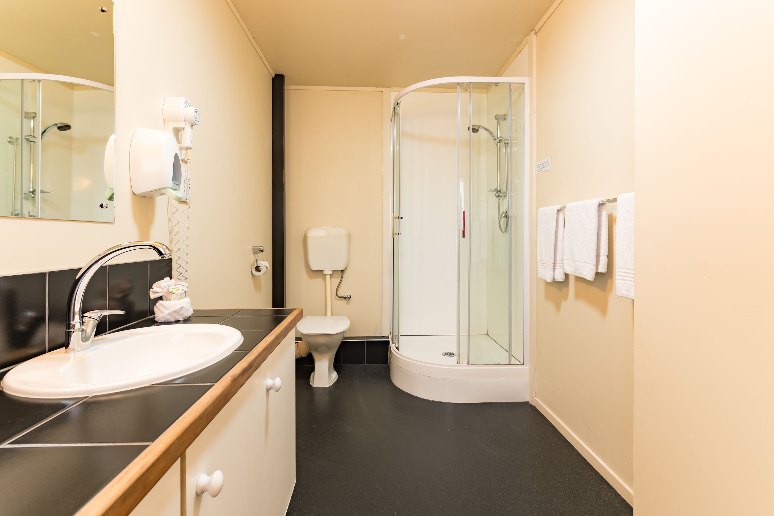 Un baño moderno con lavamanos, inodoro y ducha con mampara de vidrio.